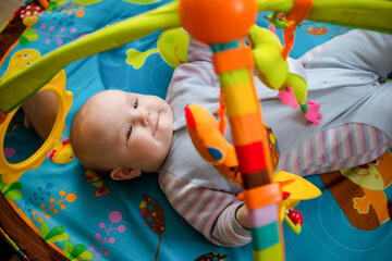 a small child lies on a children's educational play mat