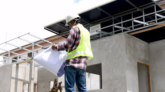 Middle-aged architect, foreman reading bluprint project paperwork standting against blue sky, engineering, small business Indian contractor male inspect unfinished real estate project workplace