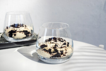 cookie and cream cheesecake in a short glass with spoon on white table. - Powered by Adobe