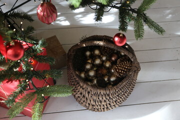 Basket with pine cones on the wooden floor near the Christmas tree