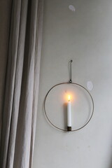 candle in a round candlestick on a white wall