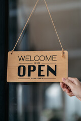 Successful small business owner holding open sign.