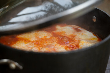 Shakshouka, a traditional dish of poached eggs in a sauce of tomatoes, harissa, olive oil, red peppers, onion and garlic, spiced with cumin, paprika and cayenne pepper