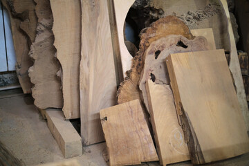Rough-cut wood slabs lean in a workshop, natural patterns highlighted. Eco-conscious woodcraft...