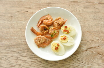 deep fried shrimp garlic and pepper with slice boiled egg  dressing chop chili in fish sauce on plate 