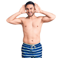 Fototapeta premium Young handsome man wearing swimwear smiling cheerful playing peek a boo with hands showing face. surprised and exited