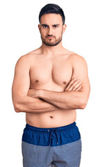 Fototapeta premium Young handsome man wearing swimwear skeptic and nervous, disapproving expression on face with crossed arms. negative person.