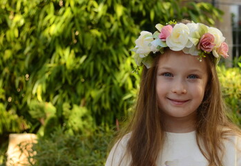 Portrait of a very beautiful girl in a wreath against a background of trees. Cute 6 year old girl with long brown hair. Natural beauty