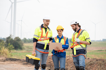 Group of male and female engineer working at wind turbines farm, discussing and inspecting quality wind turbines, planing maintenance of wind turbines at windmill field farm