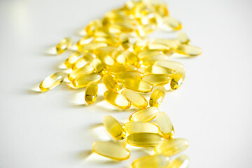 Pile of capsules Omega 3 on white table background. Close up, top view, high resolution product. Medical pill or vitamin's capsule pattern.