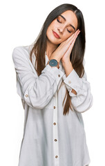 Young beautiful woman wearing casual white shirt sleeping tired dreaming and posing with hands together while smiling with closed eyes.