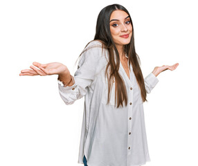 Young beautiful woman wearing casual white shirt clueless and confused expression with arms and...