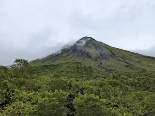 Foto op Canvas Arenal Volcano with cloud surrounding the summit in La Fortuna, Costa Rica. Green foliage and tropical jungle.  © Liam Carter
