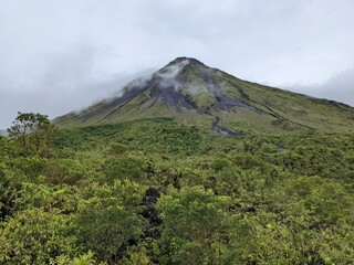 Arenal Volcano with cloud surrounding the summit in La Fortuna, Costa Rica. Green foliage and...