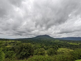 Fototapeta na wymiar Arenal Volcano with cloud surrounding the summit in La Fortuna, Costa Rica. Green foliage and tropical jungle. 