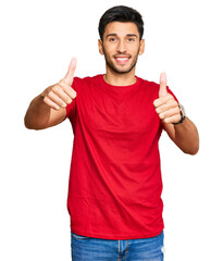 Young handsome man wearing casual red tshirt approving doing positive gesture with hand, thumbs up smiling and happy for success. winner gesture.