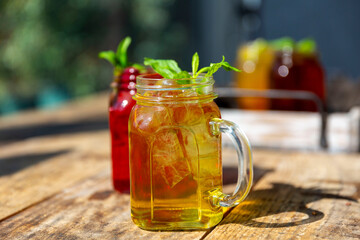 yellow and red cocktails decorated with basil standing on a wooden background with a blurred background