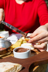 Traditional Turkish breakfast and a woman in a red sweater spreading chocolate on her bread
