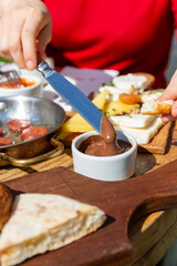 Traditional Turkish breakfast and a woman in a red sweater spreading chocolate on her bread