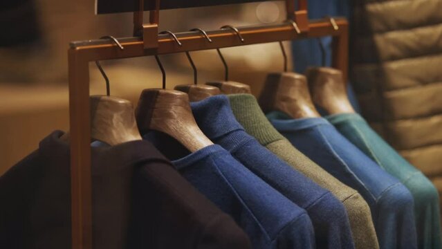 Men's wear on hangers at store. men's sweaters hanging on the rack in a clothing store, closeup. Closeup row of men's sweaters on hangers in a store. Men's retail clothing store. Shopping concept.
