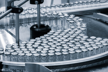 Vaccine production in a pharmaceutical factory, conveyor with the glass jars, modern pharmaceutical factory. Closeup of ampules are being filled with vaccine - obrazy, fototapety, plakaty