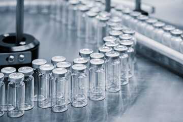Vaccine production in a pharmaceutical factory, conveyor with the glass jars, modern pharmaceutical...