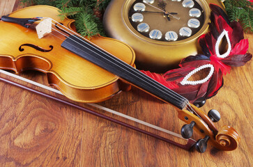 Violin with bow, carnival mask, wall clock and Christmas decorations. Symbol of the New Year's Eve.