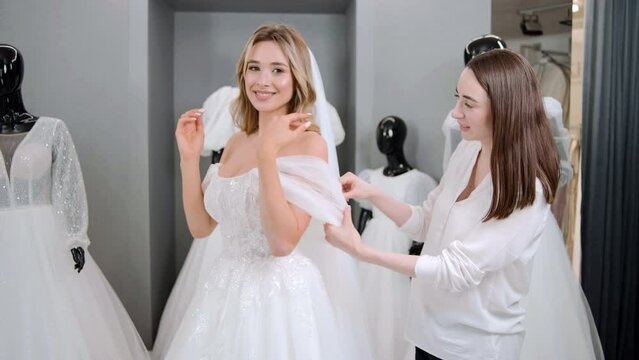 Wedding dress shop owners helping choose a bridal gown and try on a wedding dress at the wedding studio