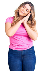 Young caucasian woman wearing sportswear sleeping tired dreaming and posing with hands together while smiling with closed eyes.