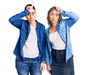 Couple of women wearing casual clothes making fun of people with fingers on forehead doing loser gesture mocking and insulting.
