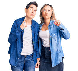 Couple of women wearing casual clothes pointing up looking sad and upset, indicating direction with fingers, unhappy and depressed.