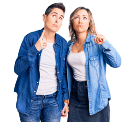 Couple of women wearing casual clothes pointing up looking sad and upset, indicating direction with fingers, unhappy and depressed.
