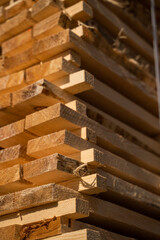 Stacked wooden planks in close-up at a outdoor lumber warehouse. Background of boards. Wood industry.