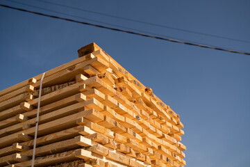 Stacked raw wooden boards at a outdoor lumber warehouse. Wood industry.