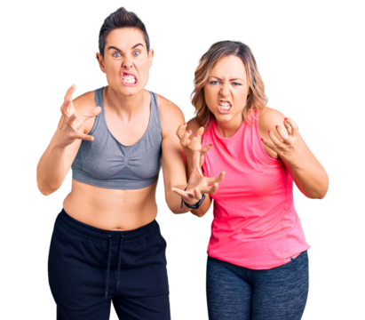 Couple of women wearing sportswear shouting frustrated with rage, hands trying to strangle, yelling mad
