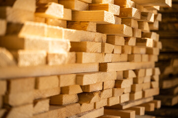 Wooden planks and beams at a indoor lumber warehouse. Stacks with pine lumber. Folded edged board. Wood harvesting shop.