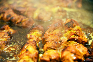 Cooking food on the street. Fried meat in sauce, close-up.