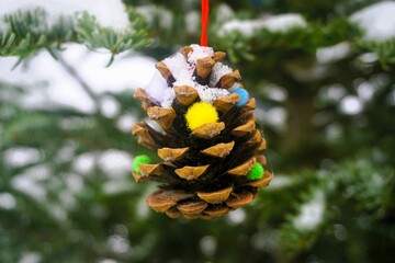 Weihnachtsdekoration mit brauner Eichel und bunten Filzkügelchen an Schneebedecktem Weihnachtsbaum...