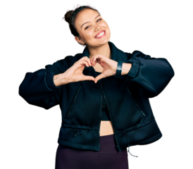 Young hispanic girl wearing sportswear smiling in love doing heart symbol shape with hands. romantic concept.