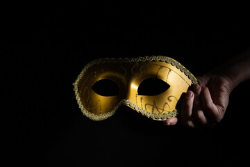 Carnival mask in hand, masquerade piece, black background