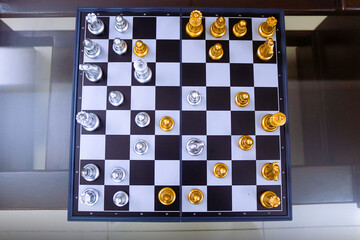 Chess board is decorated with checkers, pawns, knights, rooks, bishops, queens and kings, silver and gold colors. Chess is a popular game because of its concept, competition and strategy