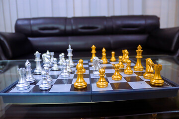 Chess board is decorated with checkers, pawns, knights, rooks, bishops, queens and kings, silver and gold colors. Chess is a popular game because of its concept, competition and strategy