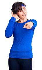 Beautiful young woman with short hair wearing training workout clothes smiling doing talking on the...