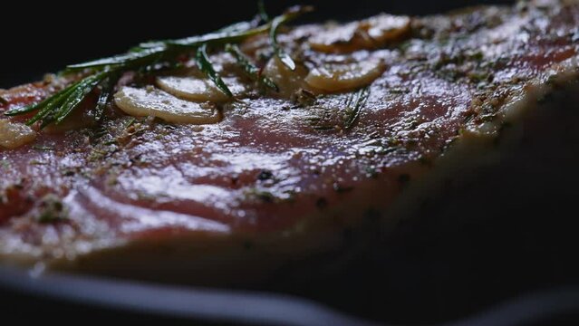 Raw tomahawk steak with seasonings on pan.