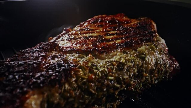 Seasoned tomahawk steak is cooked in a frying pan.