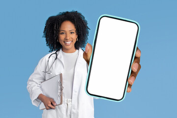 African American doctor woman shows smartphone with blank screen, studio
