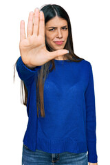 Young hispanic woman wearing casual clothes doing stop sing with palm of the hand. warning expression with negative and serious gesture on the face.