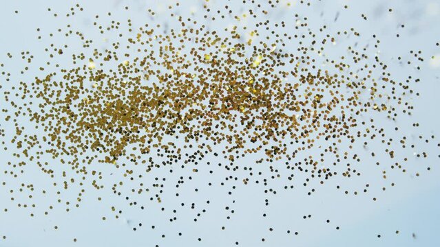 Gold confetti falling on white  background. Gold glitter slow motion abstract background. Golden Glitter Sparkling Magic light.  luxury, wealth concept, trendy holiday background.