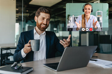 Fototapeta premium Handsome positive caucasian businessman talking with business partners via laptop