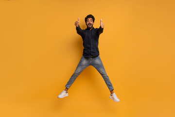 Joyful Indian Man Jumping In Air And Showing Thumbs Up At Camera